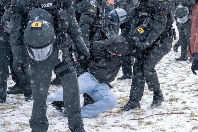 Polizisten bringen am Rande einer Demonstration eine Person zu Boden.  | Foto: Pia Bayer/dpa