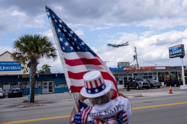 Ein Unterst&uuml;tzer h&auml;lt eine U...lm Beach International Airport landet.  | Foto: Ben Curtis/AP/dpa