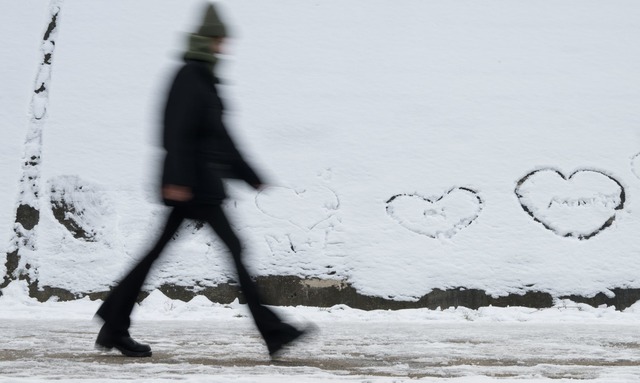 Winterwetter in Berlin: Eine Person ge...der im Schnee Herzen geschrieben sind.  | Foto: Sebastian Gollnow/dpa