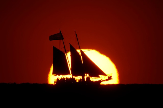 Ein Segelboot zeichnet sich gegen die ...von Treasure Island in Florida segelt.  | Foto: Charlie Riedel/AP/dpa