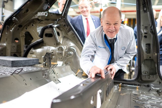 Bundeskanzler Olaf Scholz legt im VW-W...en eine D&auml;mmmatte in einen Wagen.  | Foto: Sina Schuldt/dpa