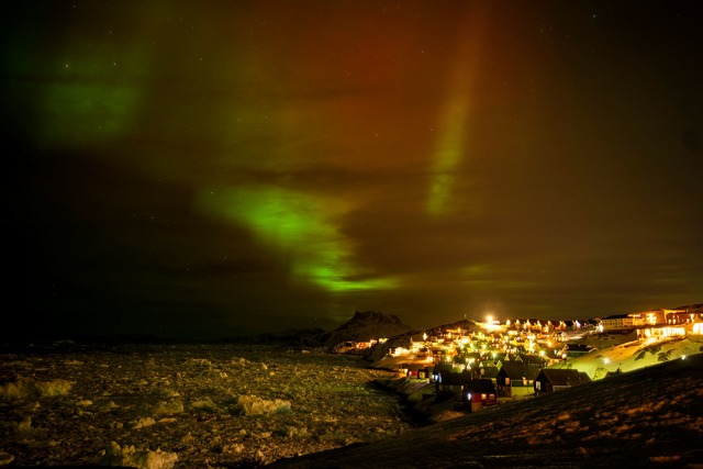 Polarlichter leuchten am fr&uuml;hen D...r H&auml;usern in Nuuk, Gr&ouml;nland.  | Foto: Emilio Morenatti/AP/dpa