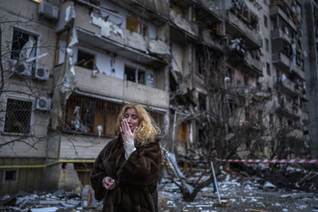 Kiew im Februar 2022: Eine Frau steht ...cher Raketenangriff hatte es zerstrt.  | Foto: Emilio Morenatti (dpa)