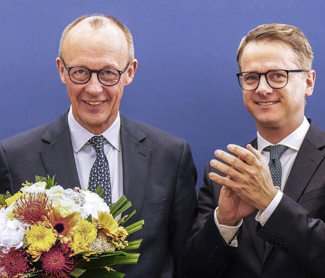 Wahlsieger mit Blumen und verhaltenem ...tes Bild) aus der ersten Reihe zurck.  | Foto: Michael Kappeler (dpa)