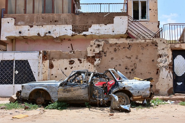 Ein zerst&ouml;rtes Auto steht im suda...s voller Einsch&uuml;sse. (Archivbild)  | Foto: Mudathir Hameed/dpa