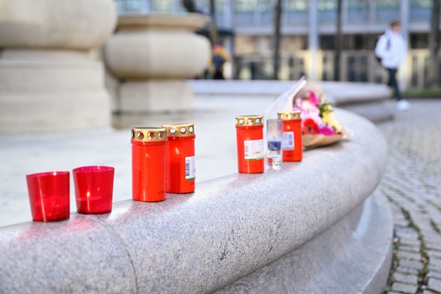 Menschen stellen Kerzen am Paradeplatz auf und legen Blumen nieder.  | Foto: Uwe Anspach/dpa