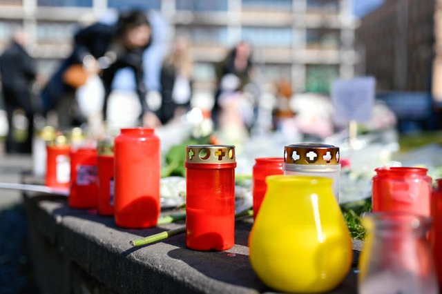 Menschen legen am Paradeplatz in Mannheim Blumen und Kerzen nieder.  | Foto: Uwe Anspach (dpa)