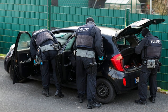 Nach Sonderzug-Gewalt: Polizeibeamte durchsuchen mehrere Pkw vor einem Wohnhaus.  | Foto: Christoph Reichwein/dpa