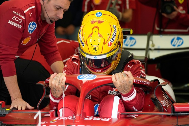 Mit gelbem Helm im roten Auto.  | Foto: Darko Bandic/AP/dpa