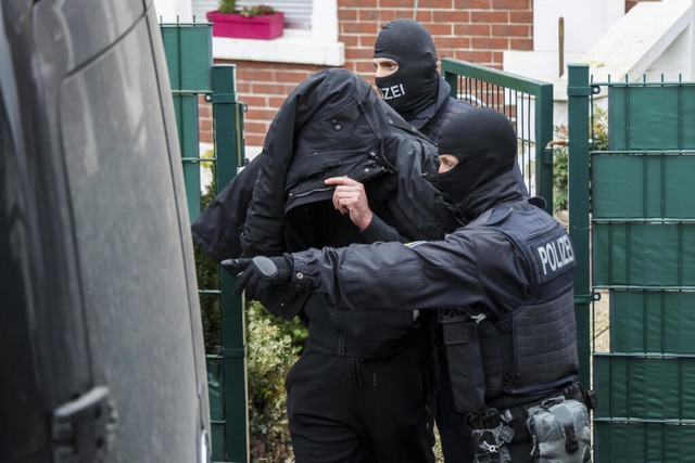 Polizeibeamte fhren einen Tatverdchtigen aus einem durchsuchten Haus in Essen.  | Foto: Christoph Reichwein (dpa) 