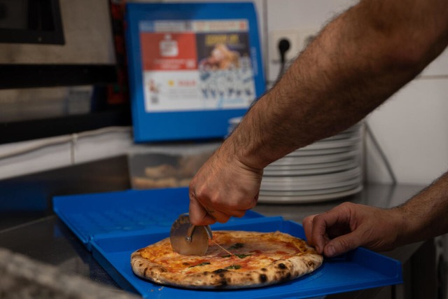 Eine Pizza wird in einer Mehrweg-Pizzaboxen geschnitten.  | Foto: Markus Lenhardt (dpa)