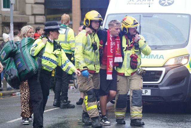 Einem Fan des FC Liverpool, der bei de...em Auto verletzt wurde, wird geholfen.  | Foto: Owen Humphreys (dpa)