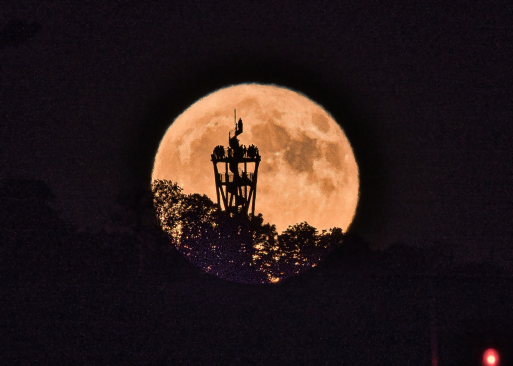 In der Silhouette des Erdbeermondes sind Schaulustige zu sehen, die sich auf dem Schlossbergturm in Freiburg versammelt haben. Peter Lewald fing diese Szene ein, als er am Mittwochabend um 23 Uhr auf dem Messeparkplatz stand.