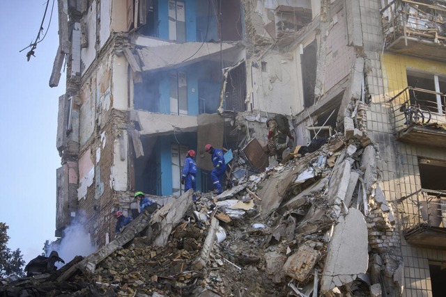 Rettungskrfte suchen nach Opfern unte...adt in ein Wohnhaus eingeschlagen ist.  | Foto: Efrem Lukatsky (dpa)