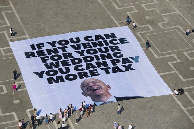 Mit einem Plakat auf dem Markusplatz f...visten, Bezos h&ouml;her zu besteuern.  | Foto: Greenpeace/Greenpeace/AP/dpa