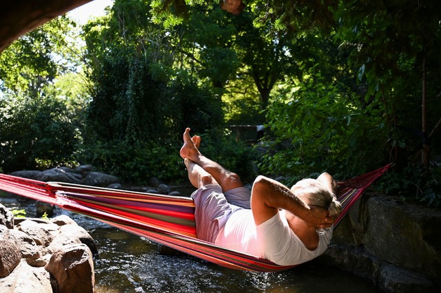 Ein Mann schaukelt im Berliner in einer H&auml;ngematte &uuml;ber dem Wasser.  | Foto: Katharina Kausche/dpa