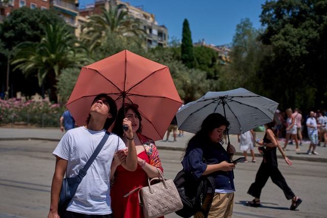 Touristen sch&uuml;tzen sich amvor der...milia mit Regenschirmen vor der Sonne.  | Foto: Emilio Morenatti/AP/dpa