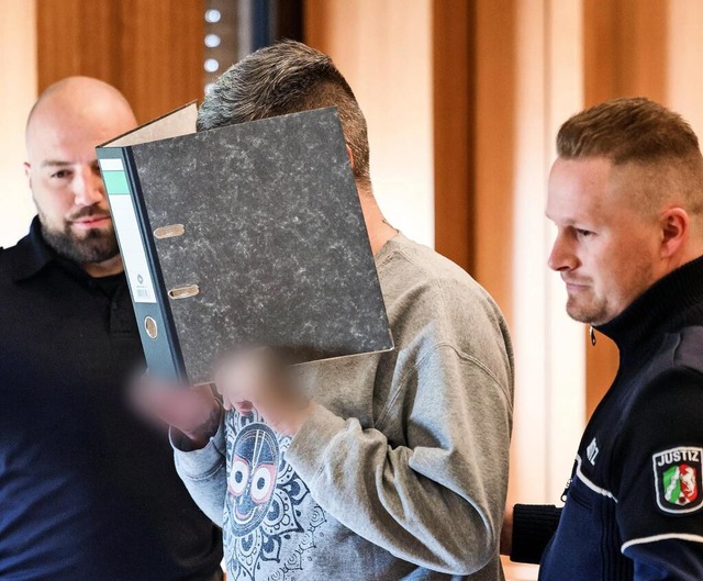 Er muss lange in Haft: Der angeklagte ...ch einen Aktenordner vor sein Gesicht.  | Foto: Oliver Berg/dpa