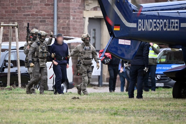 Eine Person wird von Polizeibeamten zu einem Hubschrauber gebracht.  | Foto: Uli Deck/dpa