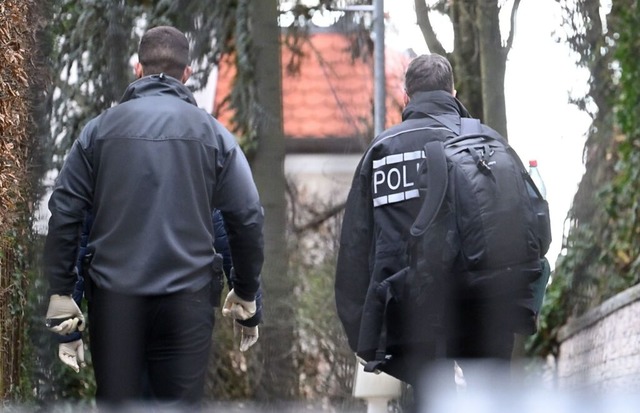 Polizisten gehen in eine Einfahrt zu einer  Villa.  | Foto: Marijan Murat (dpa)