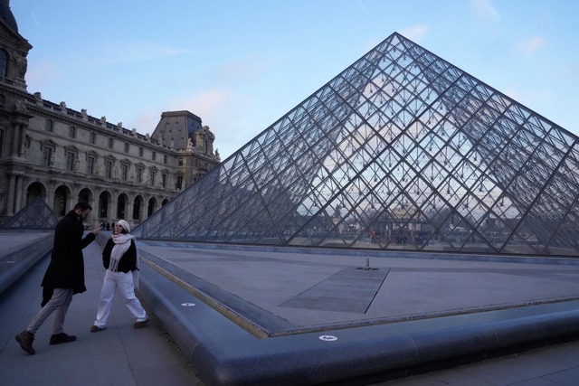 Menschen stehen an der Pyramide des Louvre-Museums am Montagmorgen.  | Foto: Michel Euler/AP/dpa