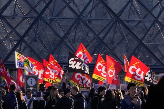 Angestellte zeigen Fahnen der Gewerkschaft CGT vor dem Louvre.  | Foto: Michel Euler/AP/dpa